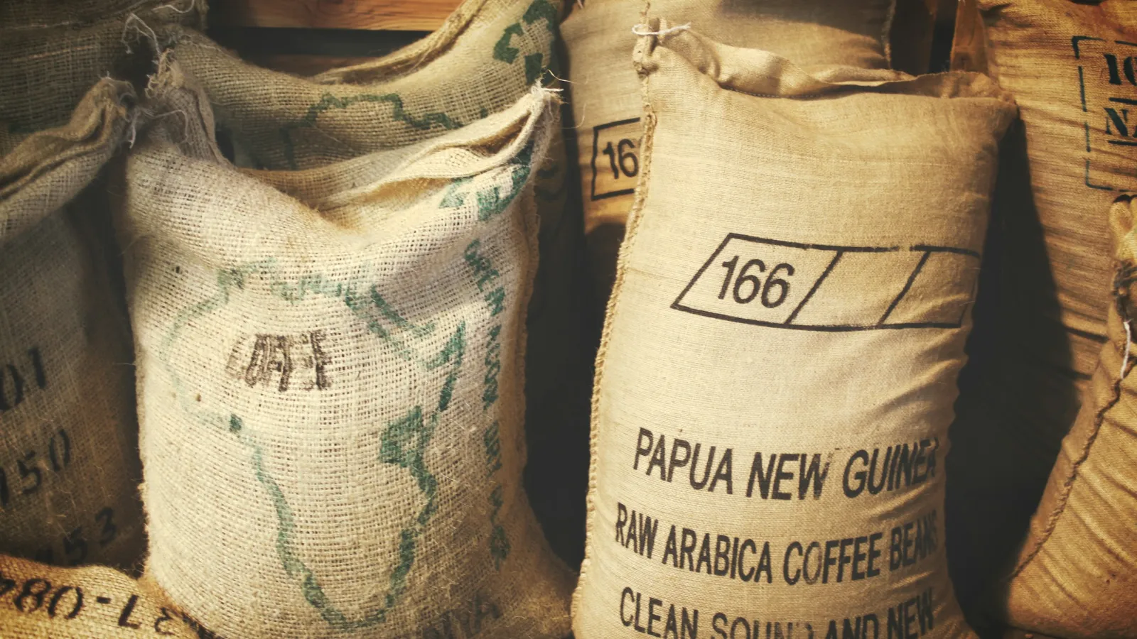 Jute sacks of green coffee stencilled "Papua New Guinea Raw Arabica Coffee Beans" with a lot number
