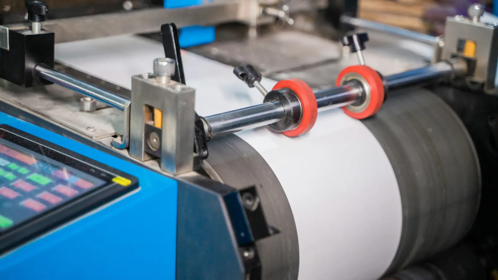 Label and paper-roll converting machine with red guide rollers and a blue control panel