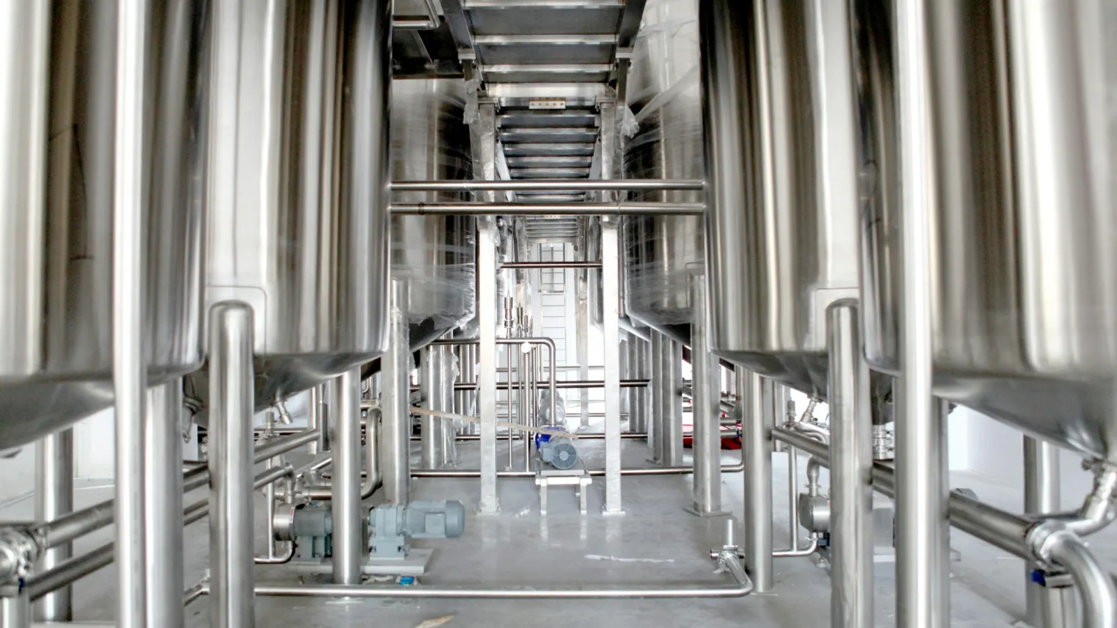 Aisle between rows of stainless-steel process tanks and pipework in a clean production hall