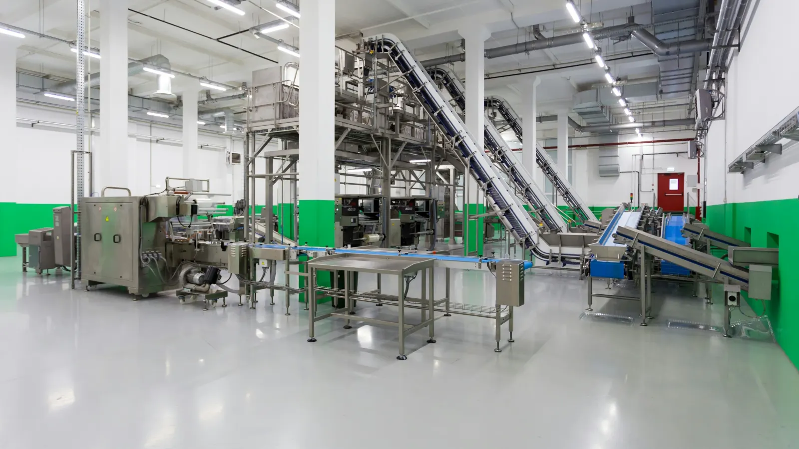 Empty food processing hall with stainless-steel conveyors and packing machines